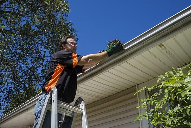 a technician repairing a rusted gutter on a house in Bigfork