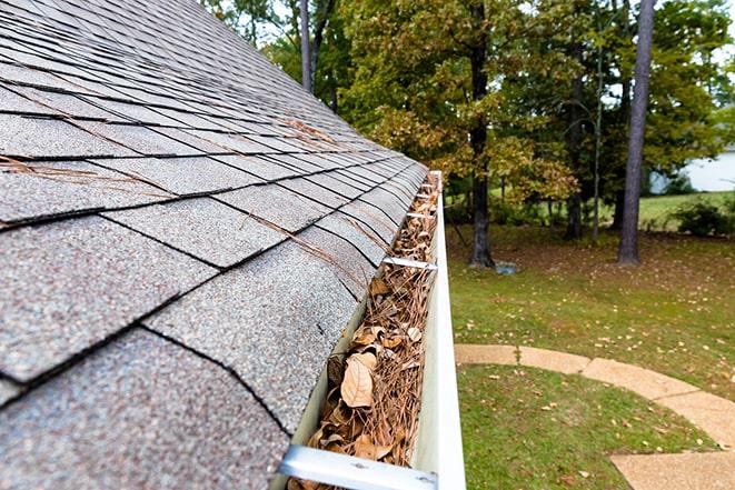 maintenance worker inspecting and cleaning residential gutter